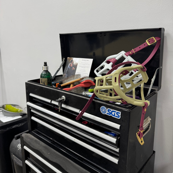 Groomers toolbox with open lid displaying various items including Dog Muzzle  and a bottle, on a white background.
