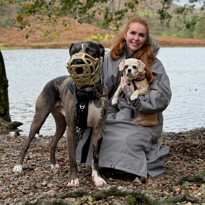 Clara, Founder and Owner of The Muzzle Movement, sitting near water with her dogs
