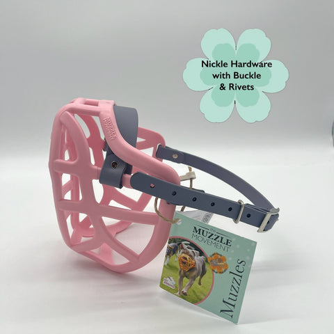 Pink dog muzzle with black hardware on a white background, featuring a product tag.