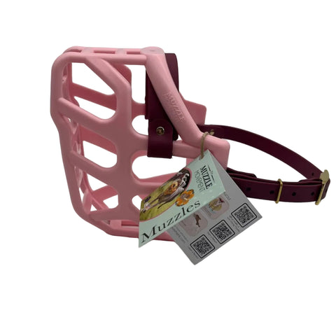 The Muzzle Movement Pastel Pink Taz dog muzzle with wine straps and brass hardware on a white background